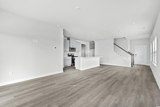 unfurnished living room featuring sink and light hardwood / wood-style flooring