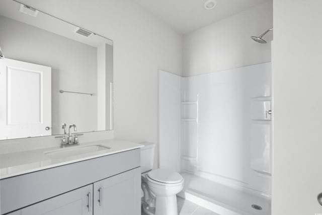 bathroom with vanity, toilet, a shower, and tile patterned floors