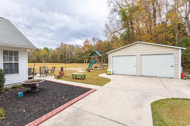 view of yard with a patio area, a garage, a playground, and an outbuilding