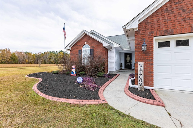 doorway to property featuring a garage, brick siding, a lawn, and a shingled roof