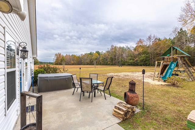 view of patio / terrace with outdoor dining area, a playground, and a hot tub