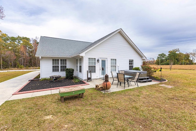 back of house with a patio, a yard, and roof with shingles