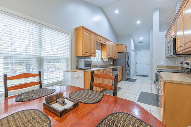 kitchen featuring high vaulted ceiling, light tile patterned flooring, stainless steel appliances, a sink, and light countertops