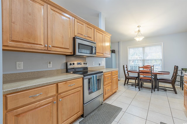 kitchen with pendant lighting, light tile patterned floors, stainless steel appliances, light countertops, and baseboards