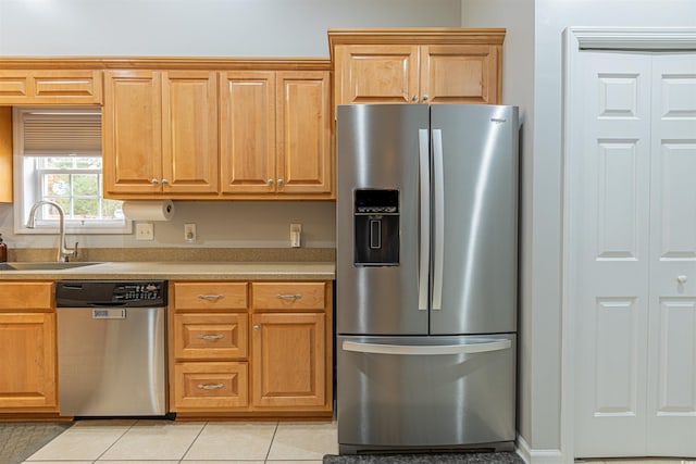 kitchen featuring light tile patterned floors, stainless steel appliances, a sink, and light countertops