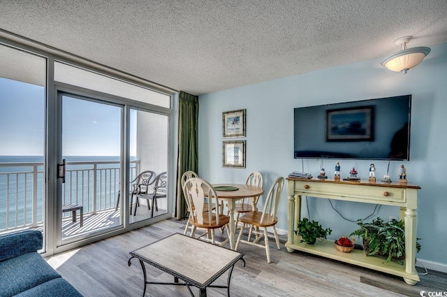 living room with floor to ceiling windows, a water view, wood-type flooring, and a textured ceiling