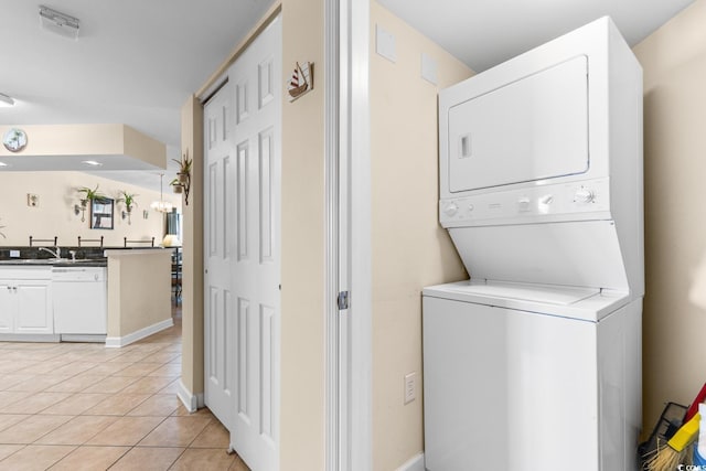 laundry area featuring light tile patterned flooring and stacked washer and clothes dryer