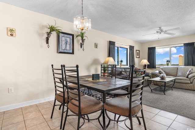 tiled dining room featuring a textured ceiling and ceiling fan with notable chandelier