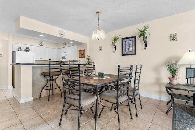 dining space with a chandelier, a textured ceiling, and light tile patterned flooring