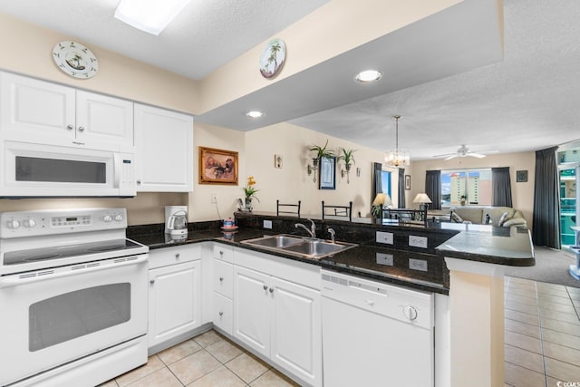 kitchen featuring white appliances, sink, a textured ceiling, white cabinetry, and kitchen peninsula