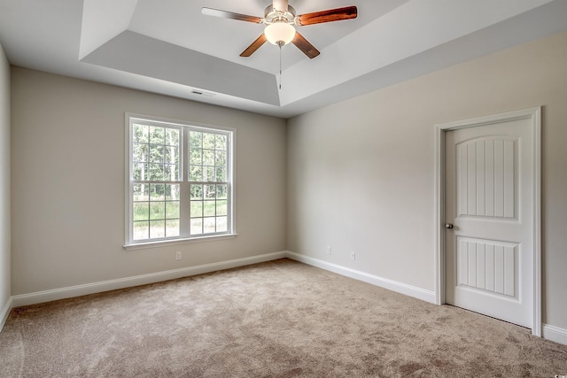 carpeted empty room featuring ceiling fan and a tray ceiling