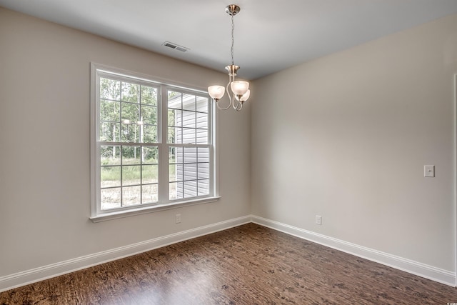 empty room with hardwood / wood-style flooring and a chandelier