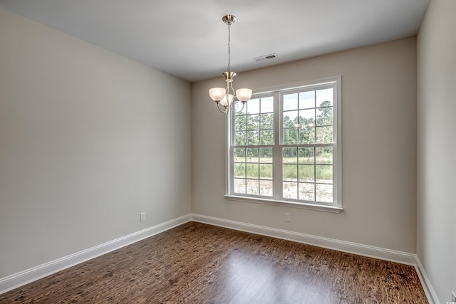 spare room featuring an inviting chandelier and dark hardwood / wood-style flooring