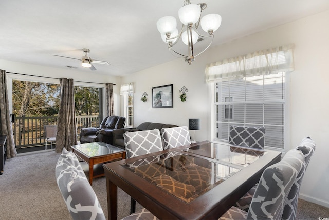 dining area with carpet and ceiling fan with notable chandelier