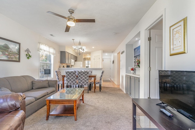 carpeted living room featuring ceiling fan with notable chandelier