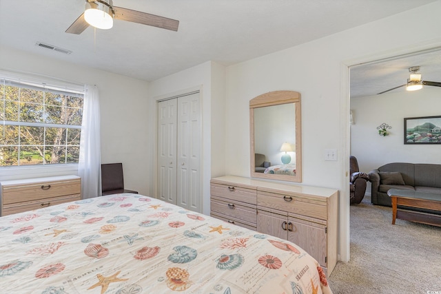 bedroom with ceiling fan, light carpet, and a closet