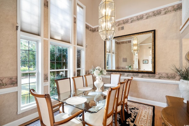 dining area featuring plenty of natural light, wood-type flooring, and a towering ceiling