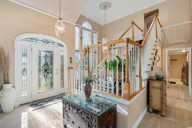 tiled foyer entrance featuring washer / dryer, high vaulted ceiling, and a notable chandelier