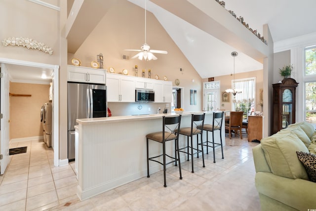 kitchen featuring appliances with stainless steel finishes, separate washer and dryer, high vaulted ceiling, white cabinets, and hanging light fixtures