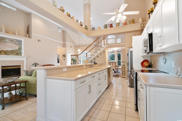 kitchen featuring white cabinets, light tile patterned flooring, a towering ceiling, and appliances with stainless steel finishes