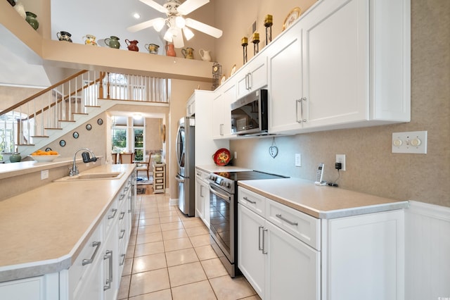 kitchen with white cabinets, stainless steel appliances, high vaulted ceiling, and sink