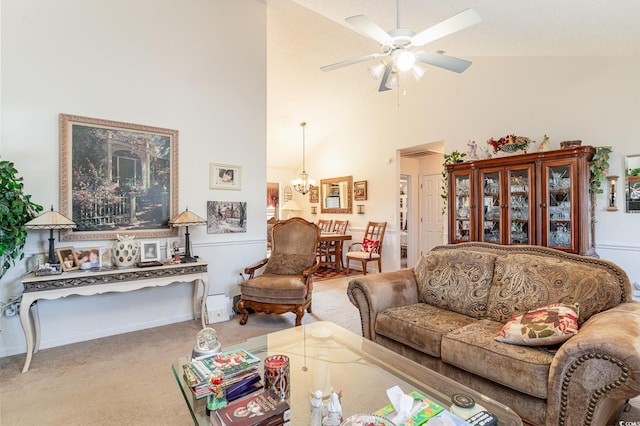 carpeted living room featuring ceiling fan with notable chandelier and high vaulted ceiling