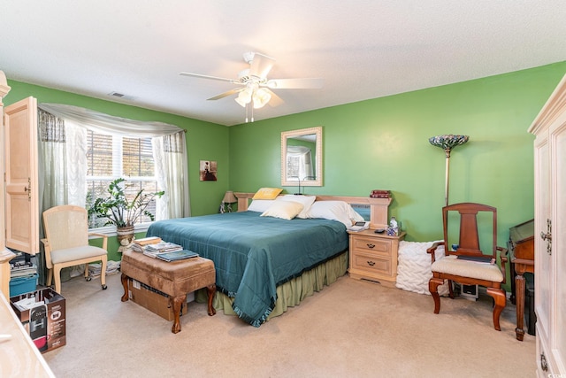 bedroom with ceiling fan, light colored carpet, and a textured ceiling