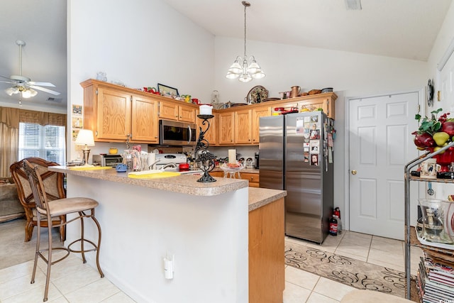 kitchen with stainless steel appliances, kitchen peninsula, a breakfast bar area, light tile patterned flooring, and ceiling fan with notable chandelier