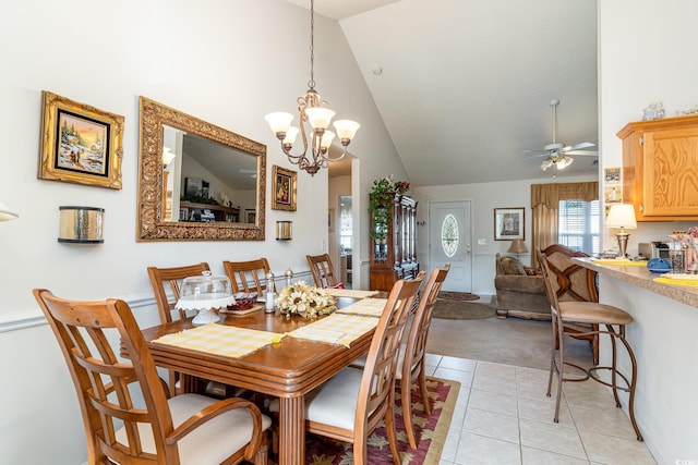 dining room with light tile patterned floors, ceiling fan with notable chandelier, and high vaulted ceiling