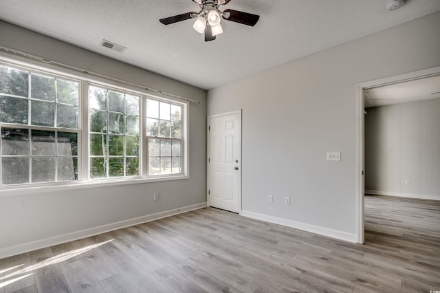 empty room with ceiling fan, light hardwood / wood-style floors, and a textured ceiling