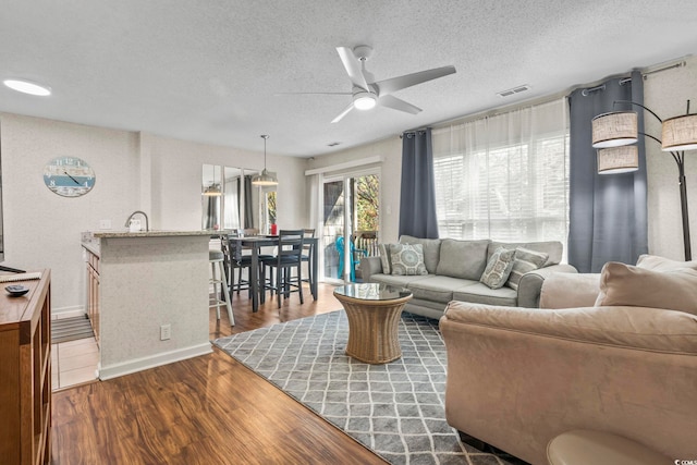 living room with ceiling fan, dark hardwood / wood-style flooring, and a textured ceiling