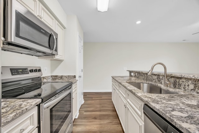 kitchen featuring sink, white cabinetry, dark wood-type flooring, light stone countertops, and stainless steel appliances