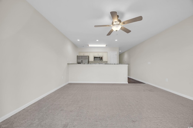 unfurnished living room with ceiling fan and dark carpet