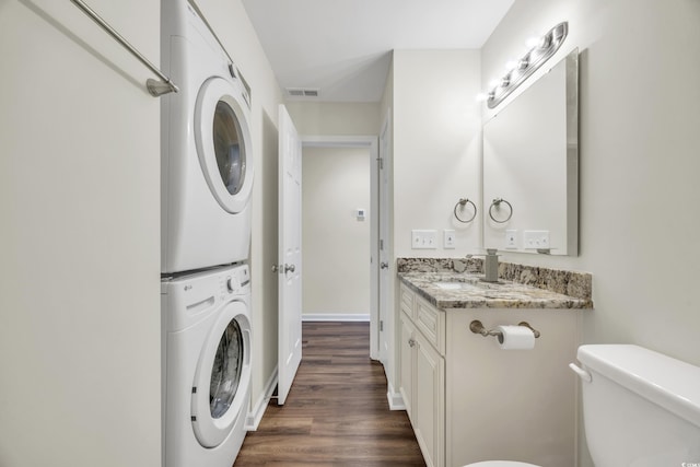 washroom featuring sink, stacked washer / drying machine, and dark hardwood / wood-style flooring