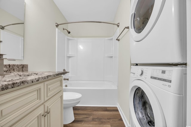 full bathroom featuring toilet, vanity, washtub / shower combination, wood-type flooring, and stacked washer / dryer