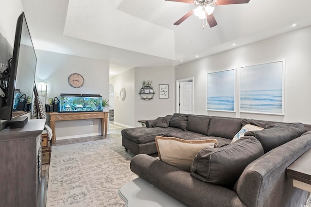 living room with ceiling fan and a raised ceiling