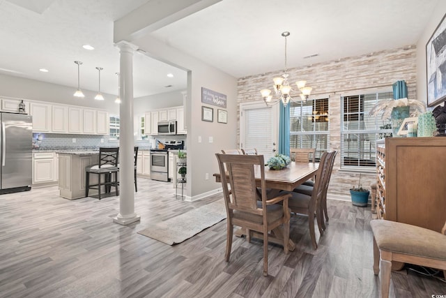 dining area featuring ornate columns, a healthy amount of sunlight, and light wood-type flooring