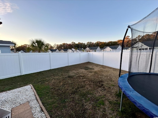 yard at dusk featuring a trampoline