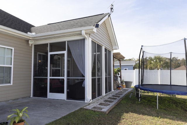 view of property exterior featuring a trampoline, a sunroom, and a patio