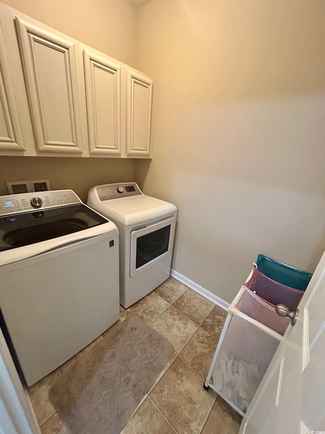 laundry room featuring cabinets, light tile patterned floors, and washing machine and clothes dryer