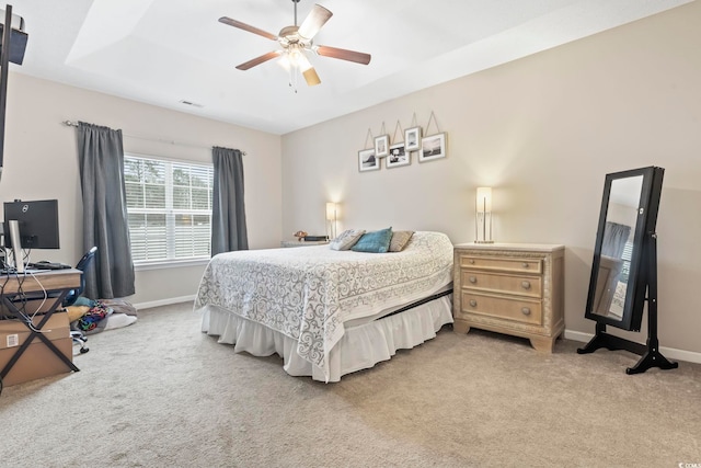 carpeted bedroom featuring ceiling fan and a tray ceiling