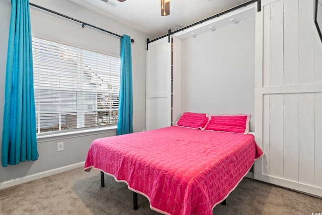 carpeted bedroom featuring ceiling fan and a barn door