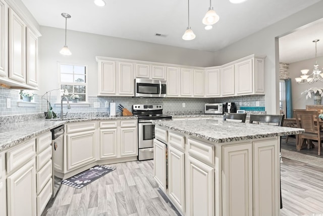 kitchen featuring stainless steel appliances, a kitchen island, pendant lighting, and white cabinets