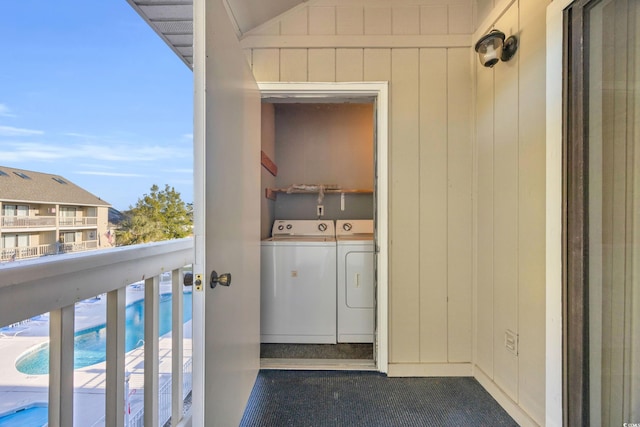 laundry area with wood walls, separate washer and dryer, and a wealth of natural light