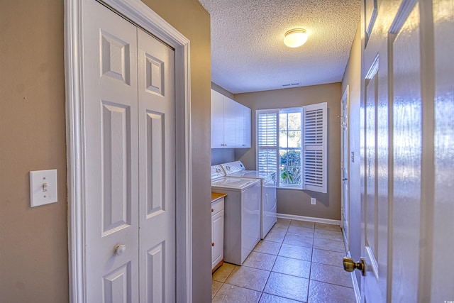 laundry area featuring washer and dryer, light tile patterned floors, cabinets, and a textured ceiling