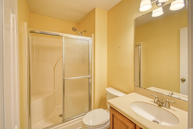 bathroom with a shower with door, vanity, a textured ceiling, and toilet