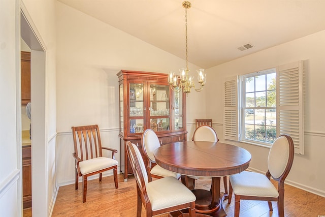 dining space with a chandelier, light hardwood / wood-style floors, and vaulted ceiling