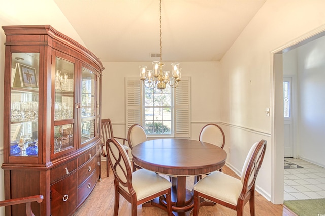 dining area featuring light hardwood / wood-style flooring, a chandelier, and vaulted ceiling