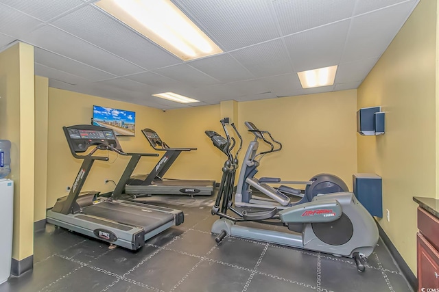 gym featuring a drop ceiling and baseboards