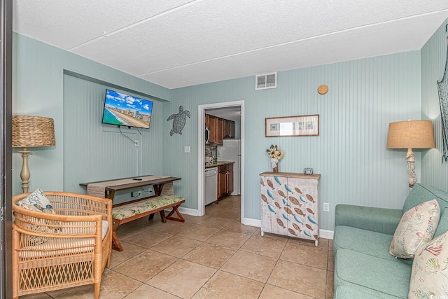 living area featuring light tile patterned floors, visible vents, and baseboards